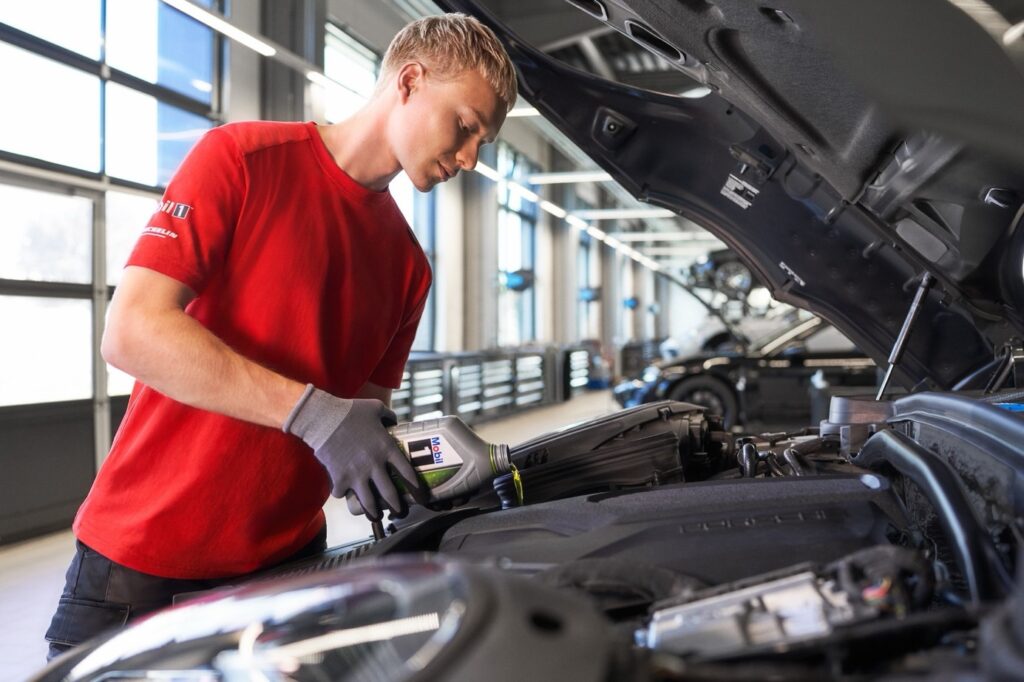 Pracownik serwisu wlewa olej Mobil 1 do silnika Porsche
